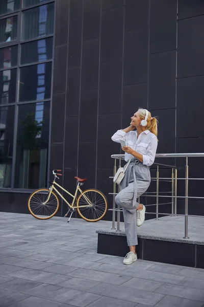 Affärskvinna vilar efter hård arbetsdag i det tomma utrymmet framför den moderna byggnaden — Stockfoto