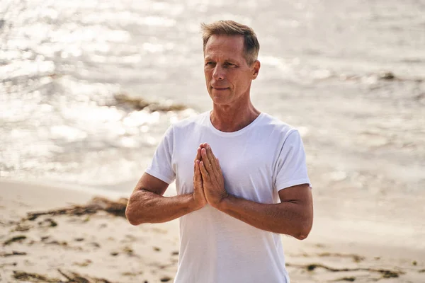 Spokojny dojrzały mężczyzna robi medytację na plaży — Zdjęcie stockowe