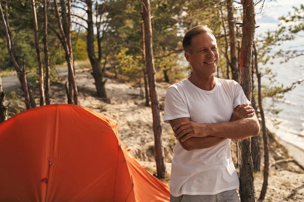 Uomo sorridente che si rilassa in campeggio in legno — Foto Stock