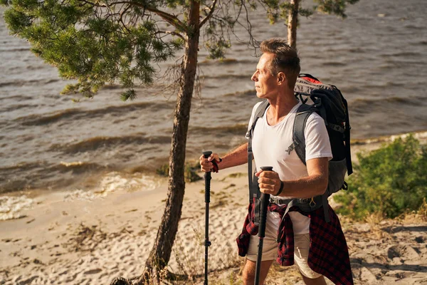 Uomo atletico che fa nordic walking vicino al mare — Foto Stock