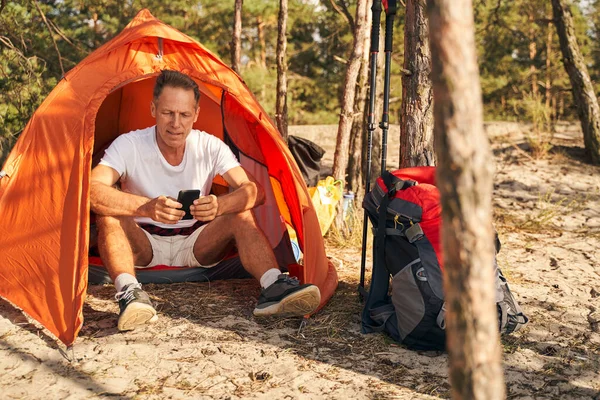 Sporty maschio andare in campeggio e riposare con il telefono cellulare — Foto Stock