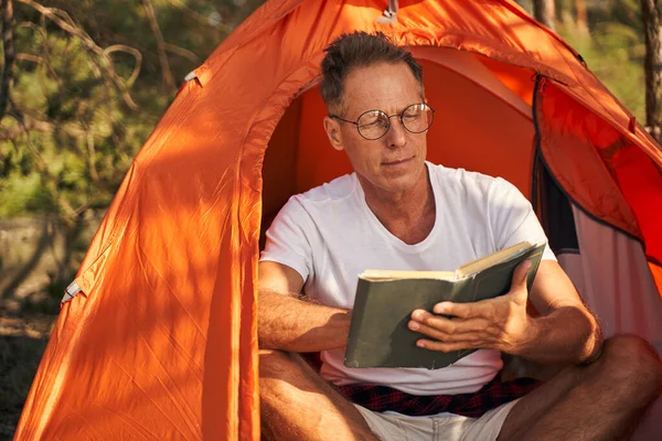 Uomo maturo godendo la lettura del libro in natura — Foto Stock