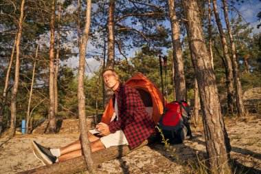 Bir adam ormanda çadırla tek başına vakit geçiriyor.