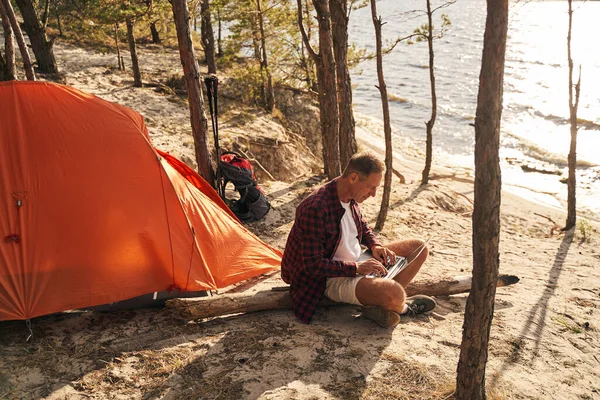 Serene male going camping with laptop in wood — Stock Photo, Image