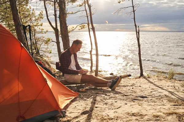 Glada man som använder surfplatta när du campar — Stockfoto