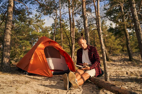 Uomo che scrive in blocco note pur avendo riposo nella foresta — Foto Stock