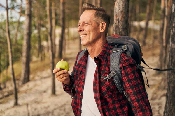 Uomo affamato mangiare mela durante le escursioni in legno — Foto Stock