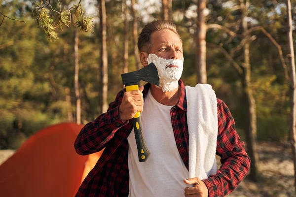 Uomo divertente utilizzando ascia per la rasatura in natura — Foto Stock