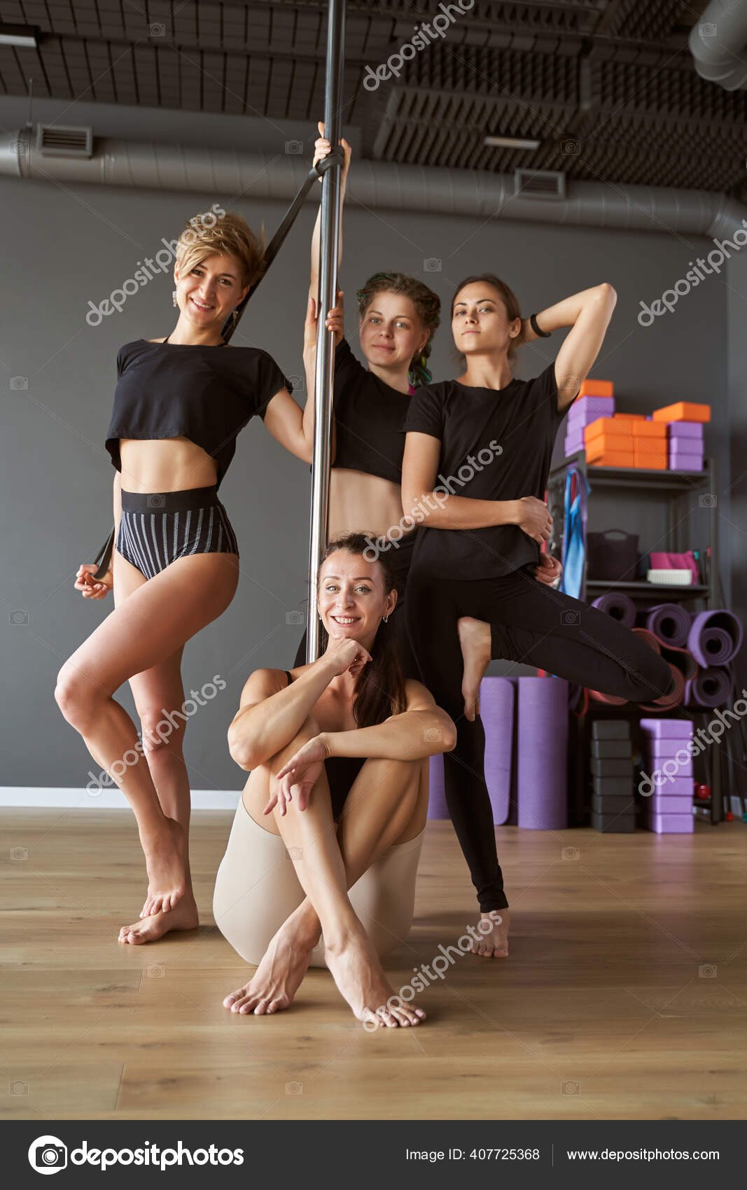 Тонкие Женщины, Стоящие И Сидящие На Пилоне В Классе Фитнеса.