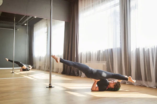 Pole dancer performing an element on the floor with the split