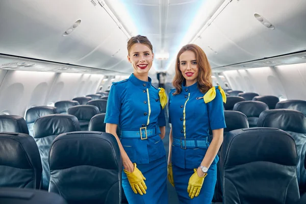 Két gyönyörű női utaskísérő a kereskedelmi repülőgép szalonjában. — Stock Fotó
