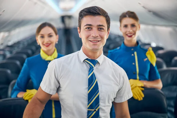 Characters steward in uniform looking at the photo camera in salon of aircraft — Stock Photo, Image