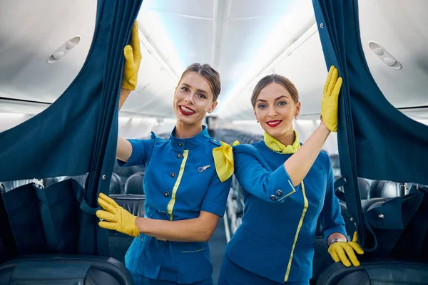 Due hostess femmine del team dell'aviazione con le labbra rosse che sorridono alla telecamera — Foto Stock