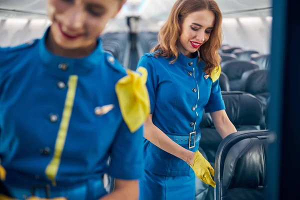 Squadra aviazione molto amichevole di hostess aeree che lavorano in salone azzurro scuro di aereo grande — Foto Stock