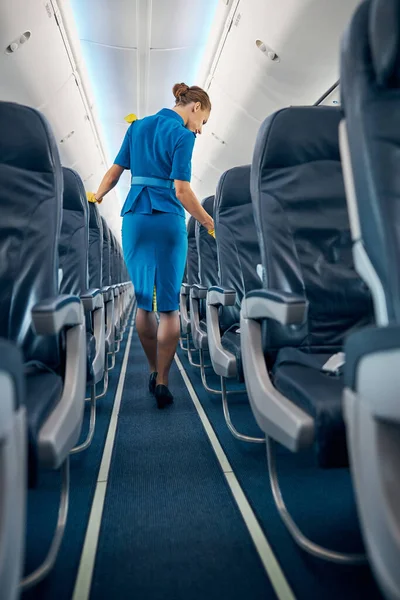 Stylish woman dressed suit walking on the board of big salon of commercial airplane — Stock Photo, Image