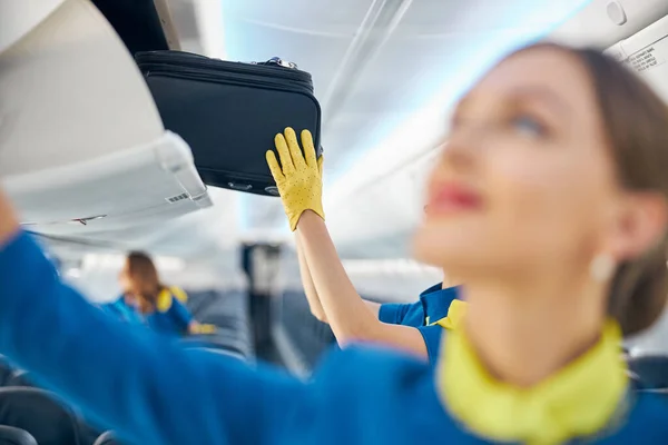 Hands of stewardess in yellow leather gloves holding rolling bag — Stock Photo, Image