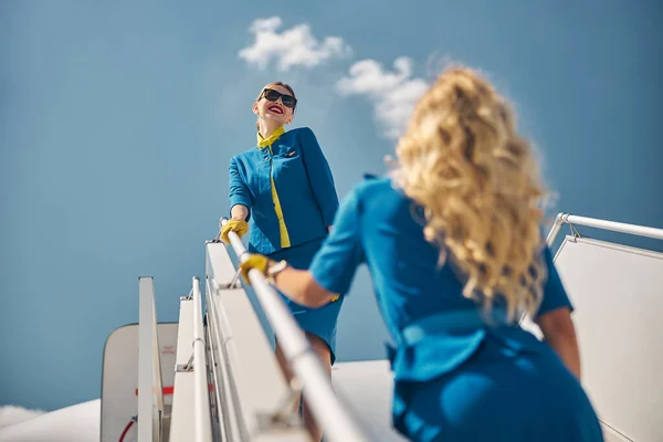 Duas belas aeromoças em pé nas escadas do avião — Fotografia de Stock