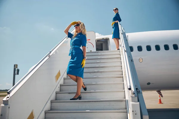 Dos bellas azafatas de pie en las escaleras del avión — Foto de Stock