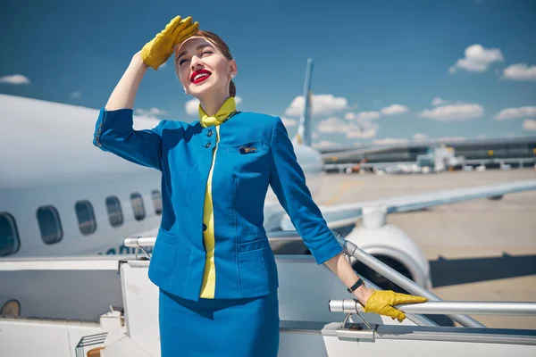 Hermosa azafata joven de pie en las escaleras del avión — Foto de Stock