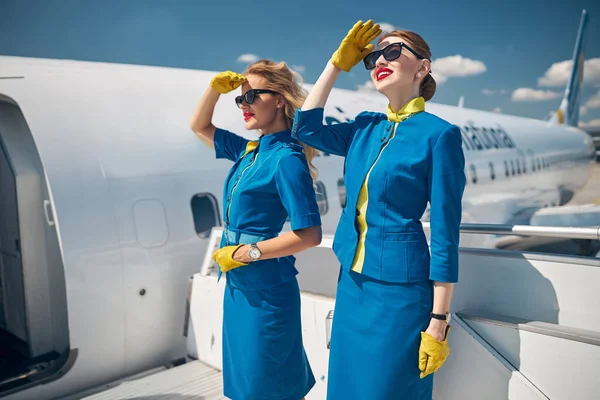 Две юные стюардессы стоят на лестнице самолета — стоковое фото