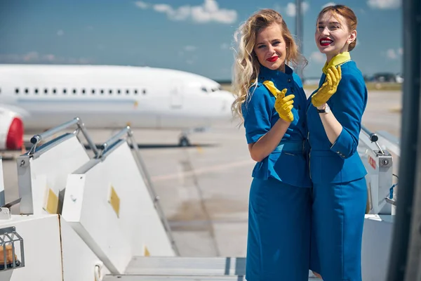 Cheerful stewardesses standing on top of boarding stairs — Stock Photo, Image