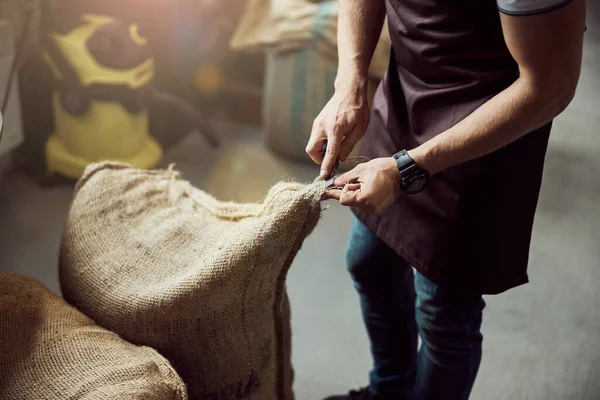 Hombre trabajador abriendo saco de arpillera con granos de café —  Fotos de Stock