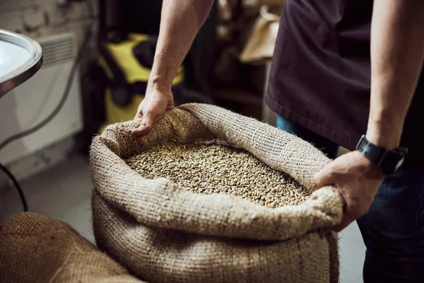 Male worker hands holding bag with green coffee beans — Stock Photo, Image