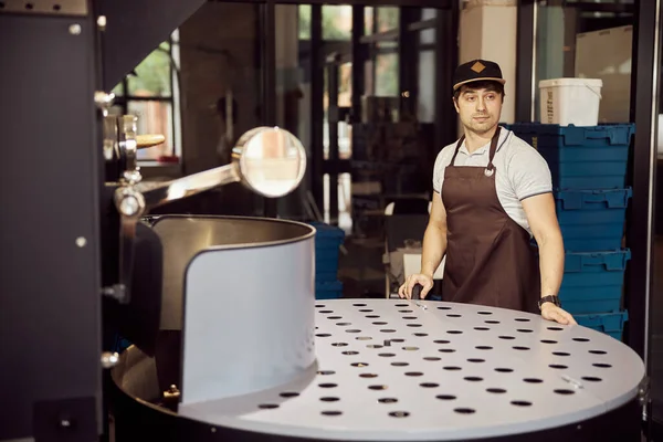 Bonito trabalhador masculino usando máquina de torrefação de café — Fotografia de Stock