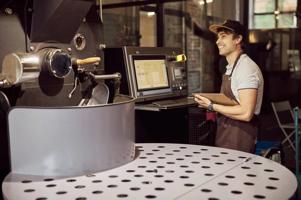 Joven alegre usando máquina de tostado de café —  Fotos de Stock