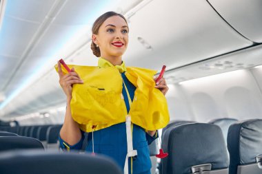 Uçuş prosedüründen önce uçakta can yeleği tutan bir uçuş görevlisi.