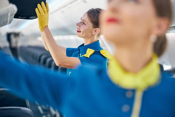 Krásná letuška pomáhá se zavazadly na palubě obchodního letadla — Stock fotografie
