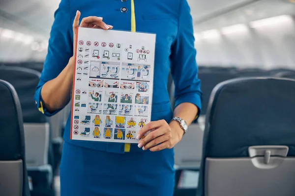 Profesionální letuška prokazující informace o bezpečnosti letu v letadle — Stock fotografie