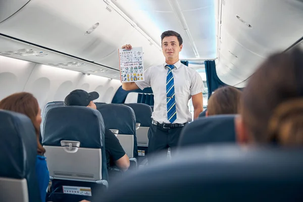 Hombre guapo sosteniendo la lista de información de seguridad para despegar vuelo —  Fotos de Stock