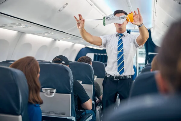 Steward demonstrating safety procedure prior to commercial airline flight took off — Stock Photo, Image