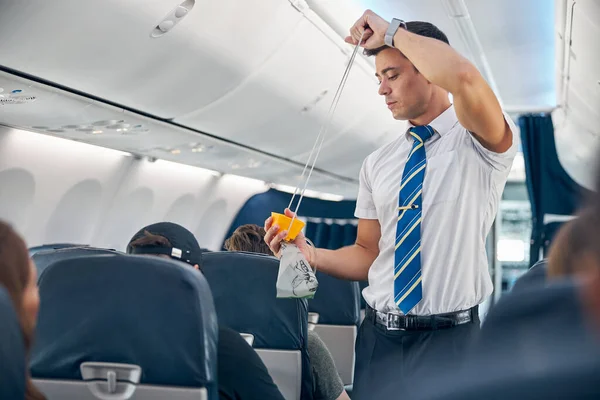 Hombre con máscara de oxígeno demostrando procedimiento de seguridad antes del vuelo del avión de pasajeros — Foto de Stock