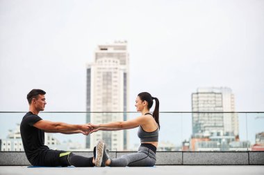 Neşeli genç çift şehir çatısında birlikte antrenman yapıyor.