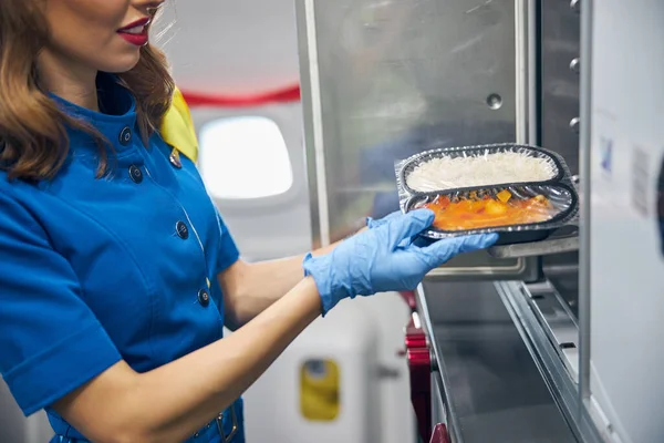 Stewardess serving food to the passengers at the kitchen of commercial airplane — Stock Photo, Image