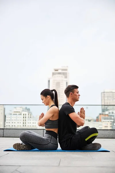 Young man and woman meditating together in city — Stock Photo, Image