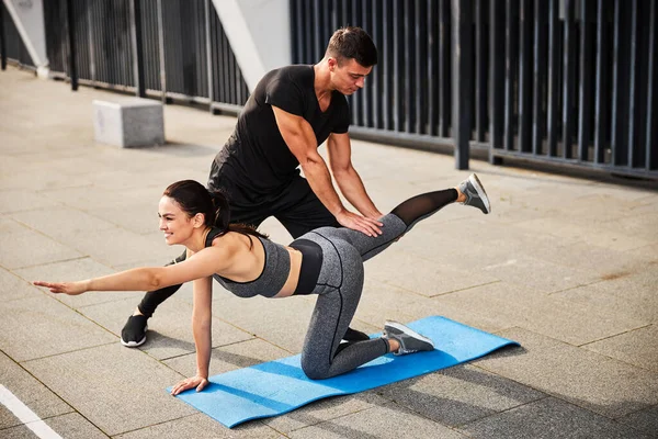 Esportivo masculino ajudando jovem mulher durante o treino ao ar livre — Fotografia de Stock