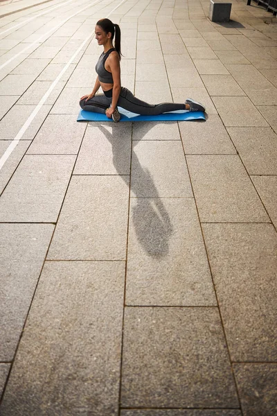 Jovem alegre exercitando no tapete ao ar livre — Fotografia de Stock