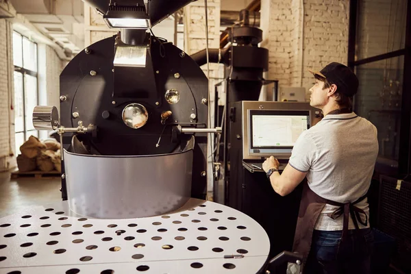 Tostador masculino profesional usando máquina de tostado de café industrial — Foto de Stock