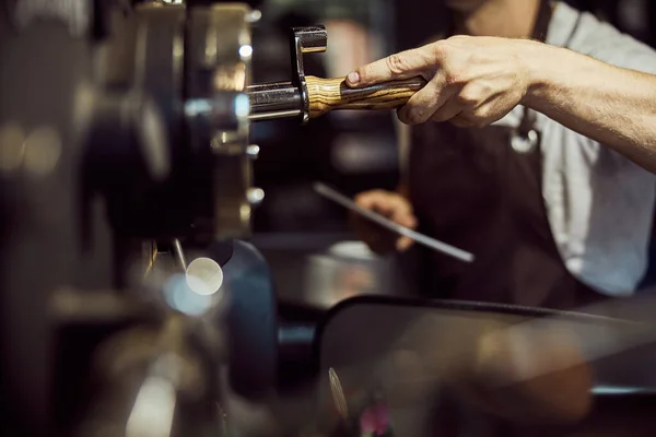Чоловік працівник експлуатує промислову машину для обсмажування кави — стокове фото