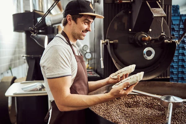 Alegre trabajador masculino sosteniendo dos tazones con granos de café — Foto de Stock