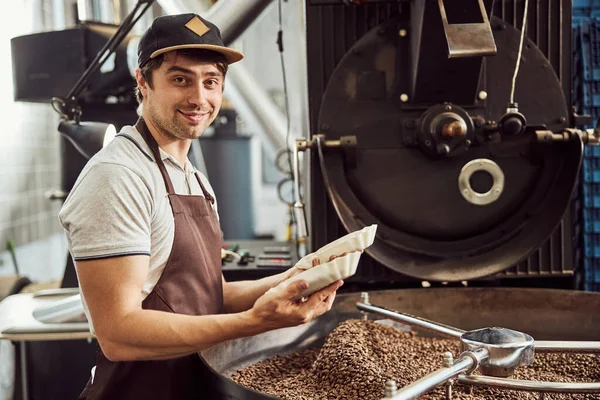 Alegre trabajador masculino sosteniendo dos tazones con granos de café — Foto de Stock