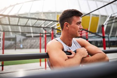 Neşeli güçlü adam açık spor alanında antrenman yapıyor.