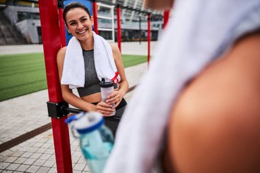 Erkek arkadaşıyla dışarıda antrenman yapan gülümseyen genç bir kadın.