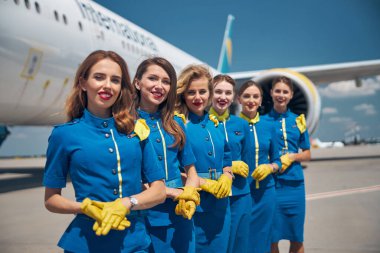 Bir grup çekici hostes havaalanının dışında dikiliyor.