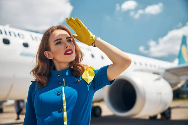 Beautiful stewardess covering her face from sun at airport — Stock Photo, Image