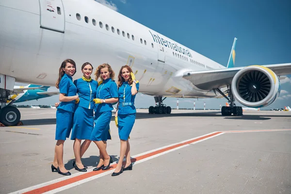 Group of beautiful stewardesses standing outdoors in airfield — Stock Photo, Image