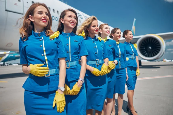 Group of beautiful young stewardesses standing outdoors in airfield — Stock Photo, Image